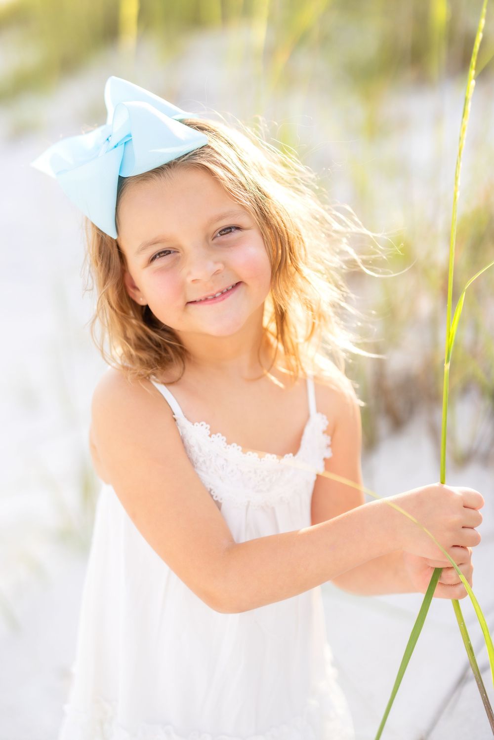 A series of four soft, dreamy portraits showing a child in white dress against a light, airy outdoor background.