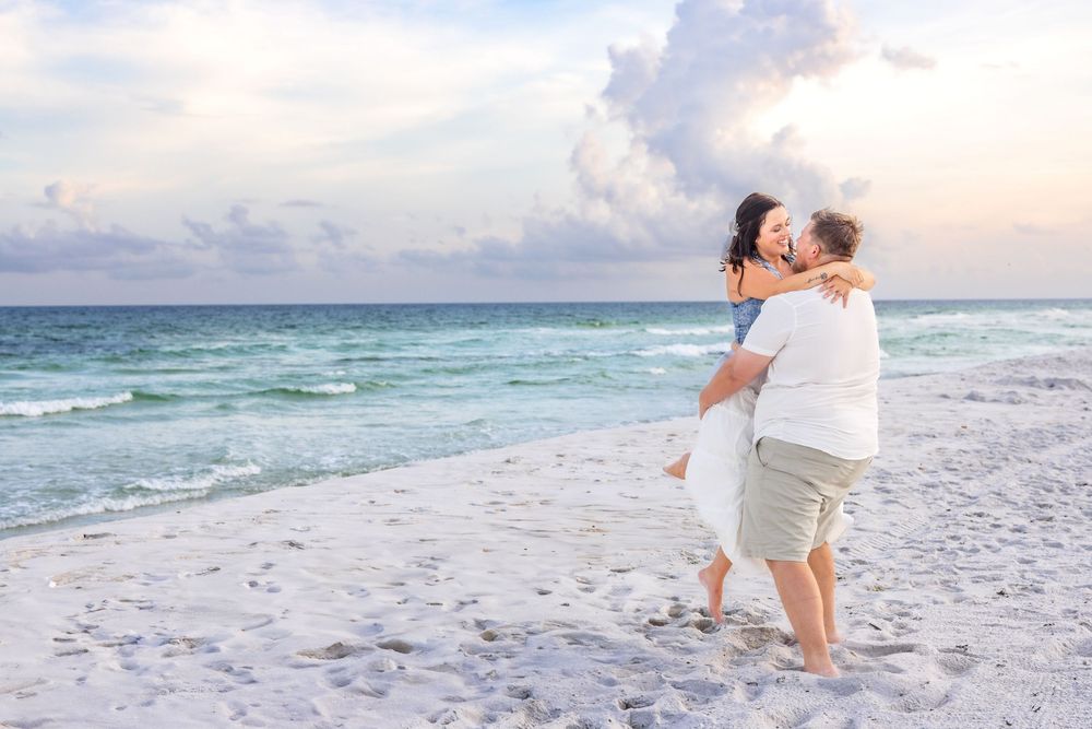 A romantic beach photoshoot at sunset captures tender moments between a couple on pristine white sand.
