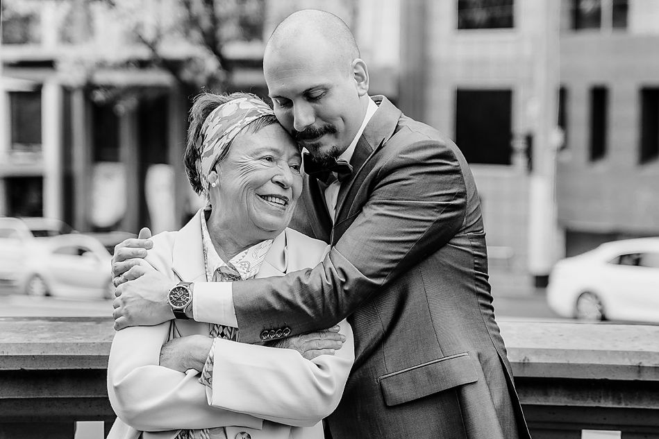 Two people embrace and laugh together in a black and white candid outdoor photo.