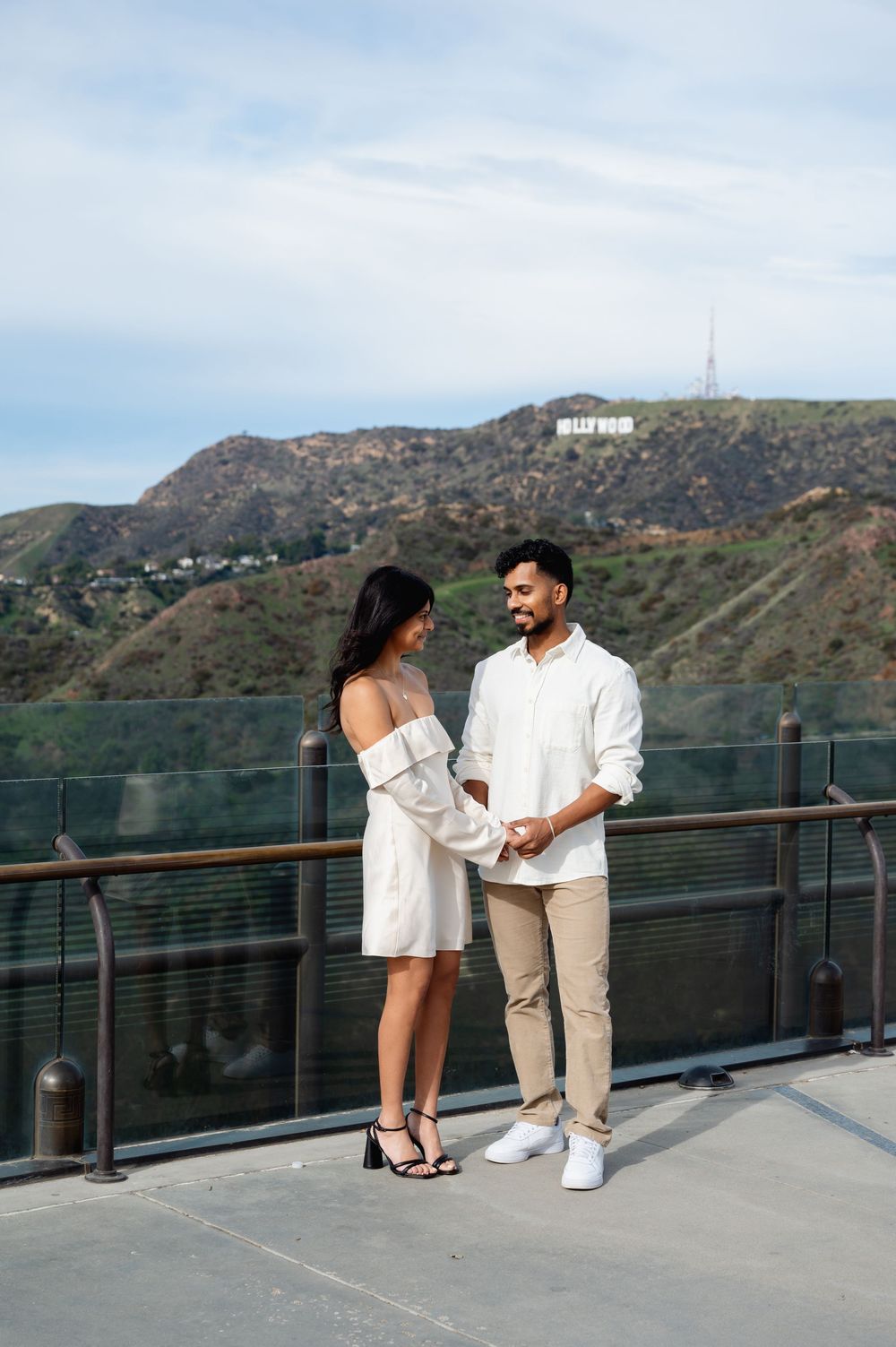 A couple shares a romantic moment on an observation deck overlooking the Hollywood Hills and iconic sign in Los Angeles.