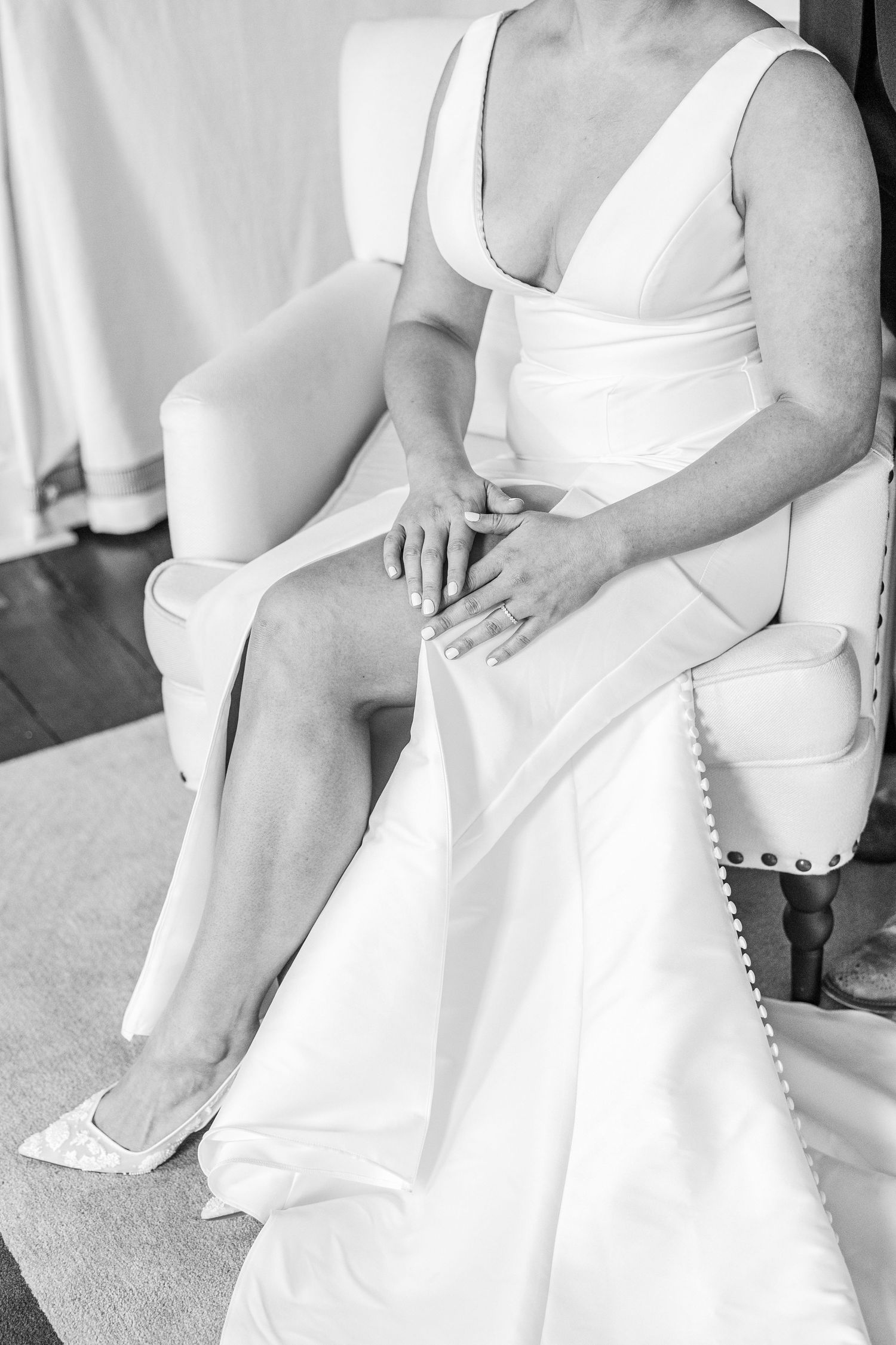A series of black and white photos showing close-up details of a white wedding dress with delicate button details.