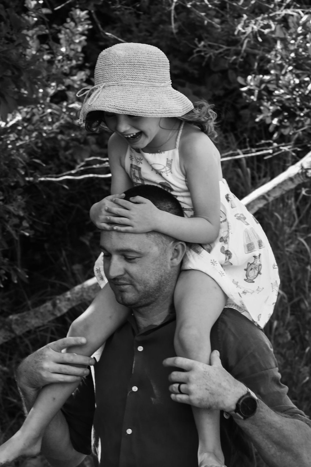 Black and white photo series showing tender moments between parent and child playing outdoors in summer hats.