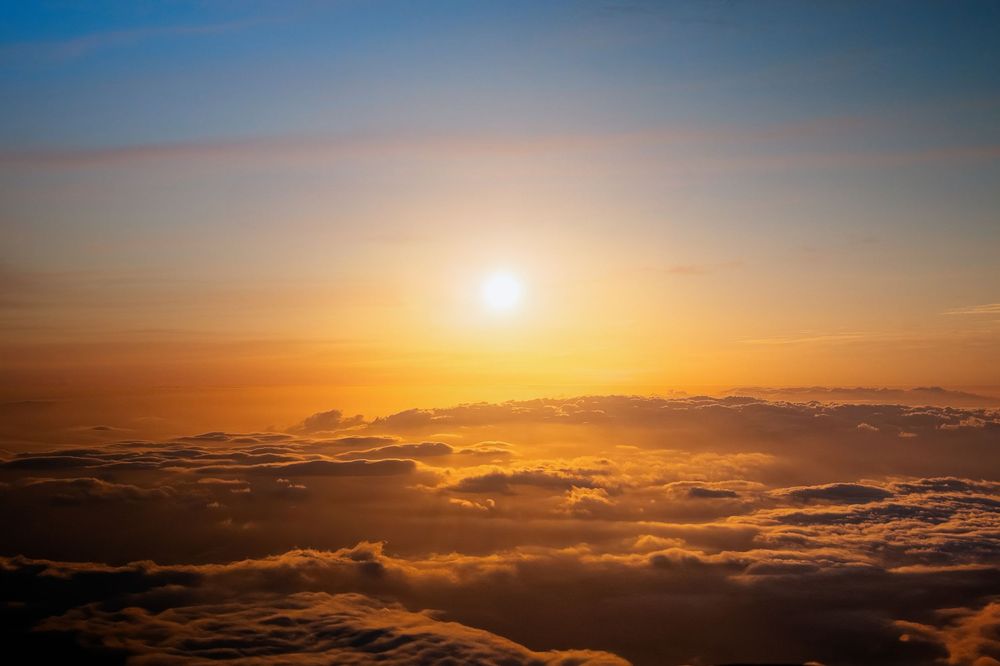 Stunning sunset view above clouds with golden sunlight illuminating the horizon.