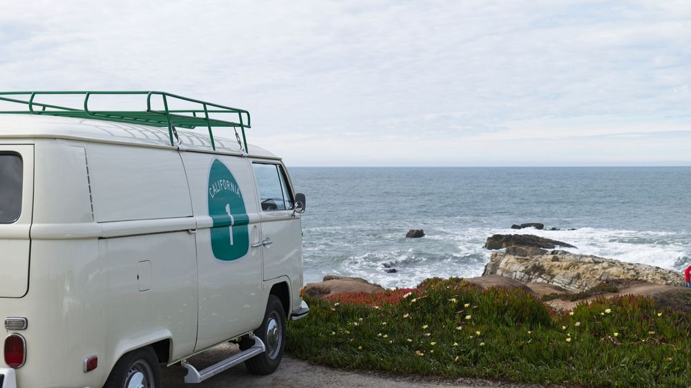 White van parked along a scenic coastal road with ocean views.