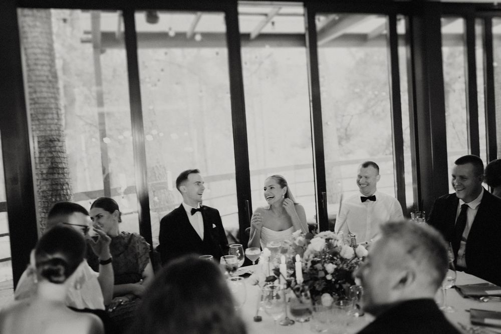 Black and white photo of wedding reception dinner with guests seated at long tables.