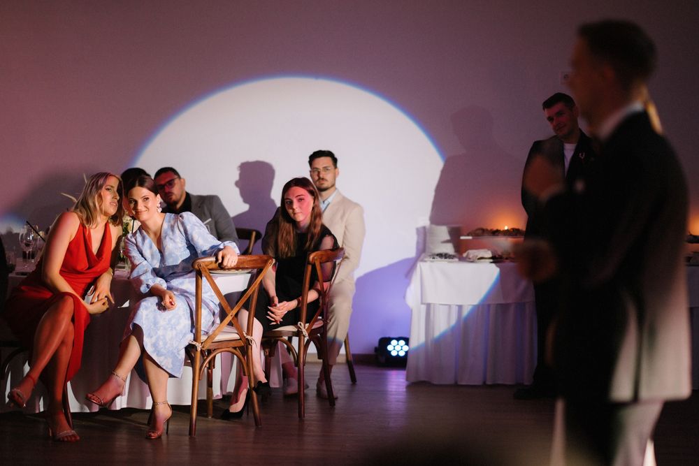 Wedding reception audience watching a presentation with dramatic lighting and projections.