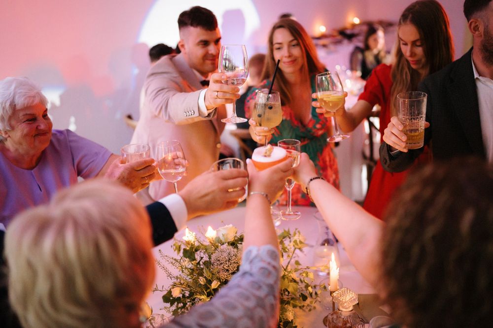 Guests raising glasses in a celebratory toast during an evening reception.