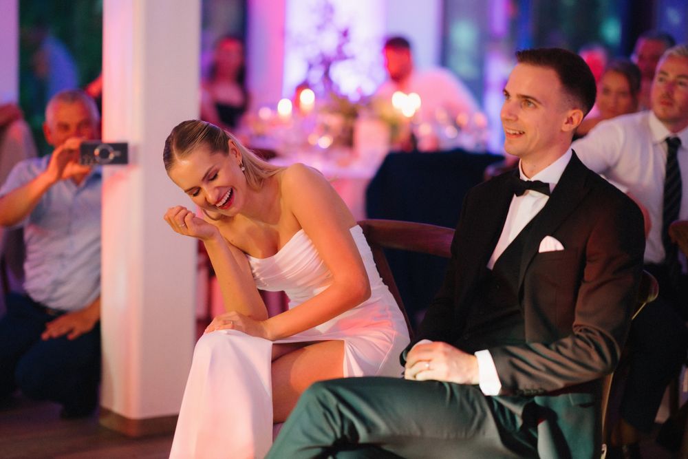Wedding celebration with guests dancing under purple mood lighting in an elegant venue.