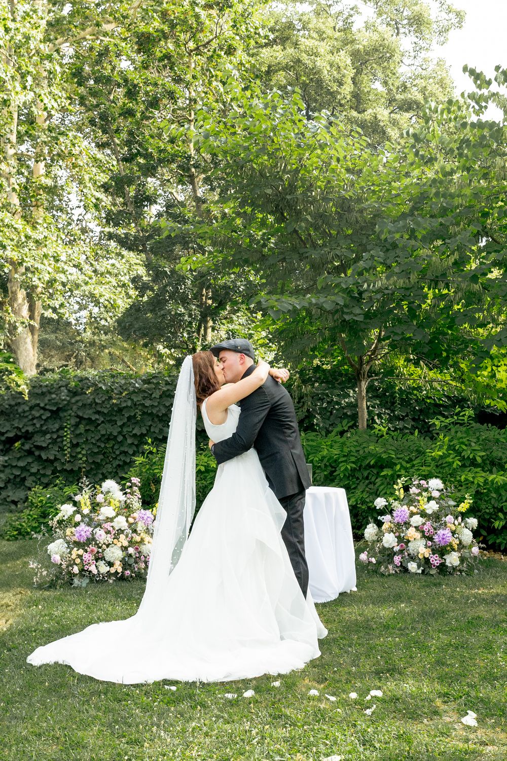 Romantic wedding couple shares intimate moments in a garden setting with beautiful floral arrangements.