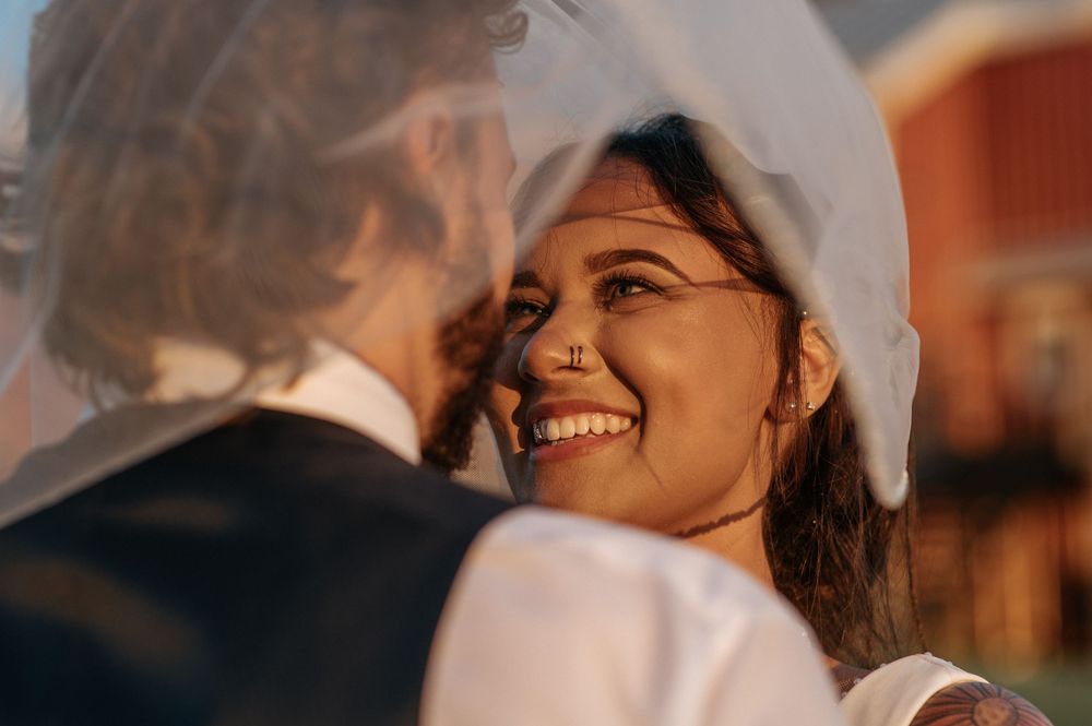 A joyful wedding moment captured during golden hour with a red barn in the background.