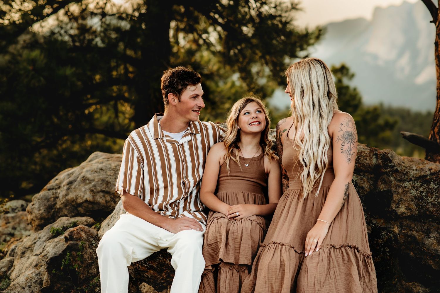 A group of friends in earth-toned outfits pose together during golden hour in a rustic outdoor setting.