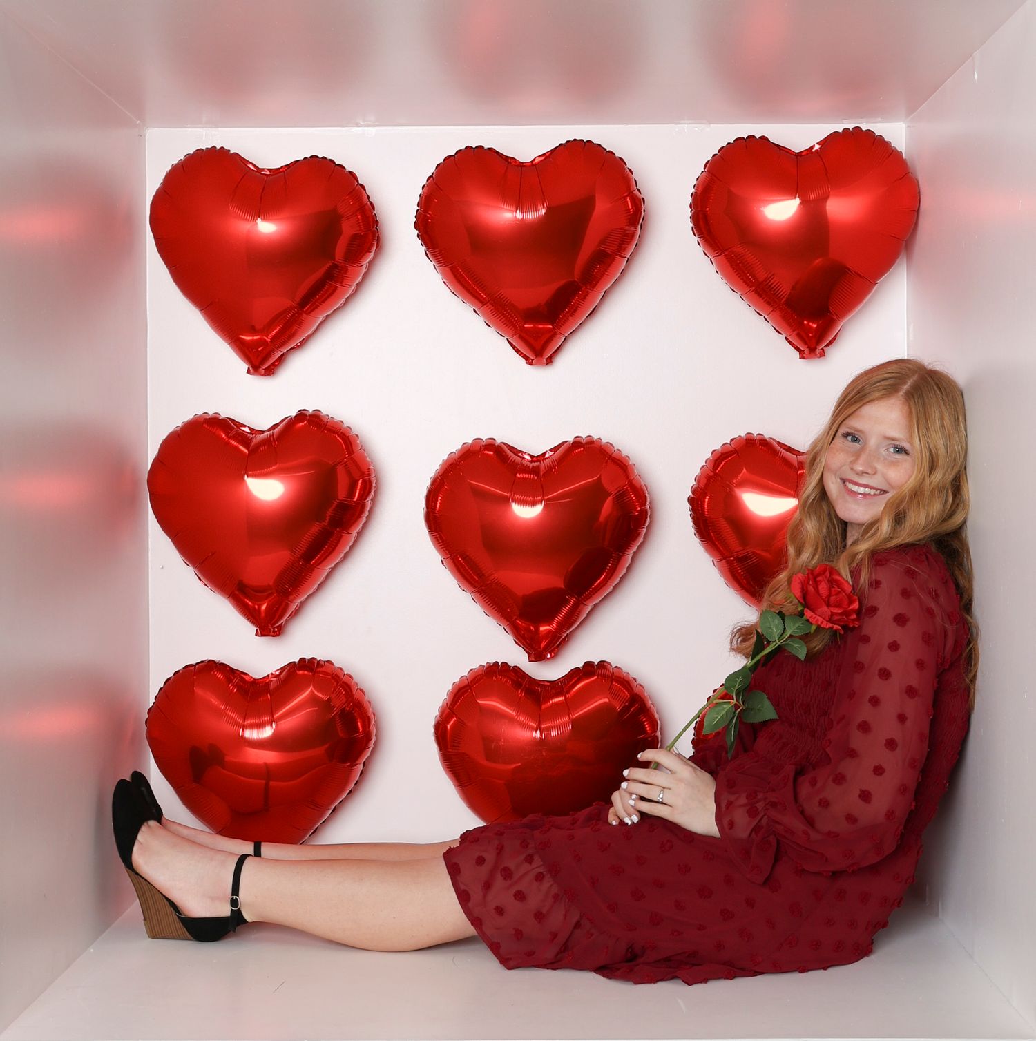 Valentine's day photo featuring red heart balloons and a person in a sparkly burgundy dress. Box photography session