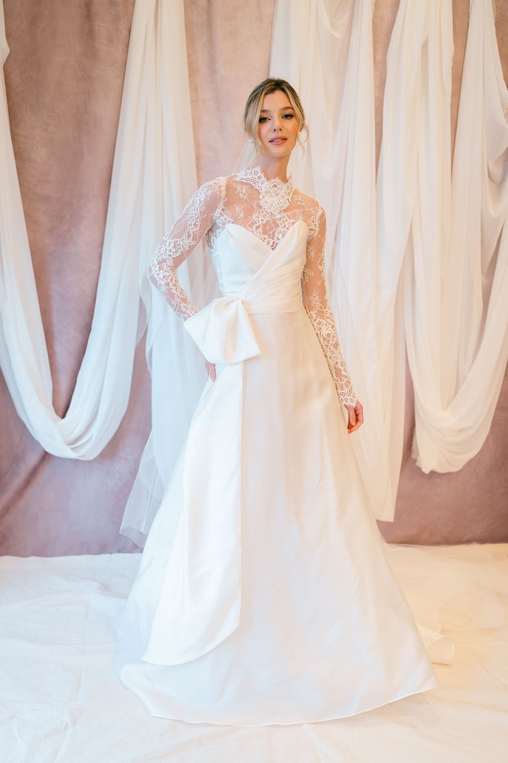 A series of elegant white wedding dresses displayed in a bridal boutique with flowing fabrics and lace details.