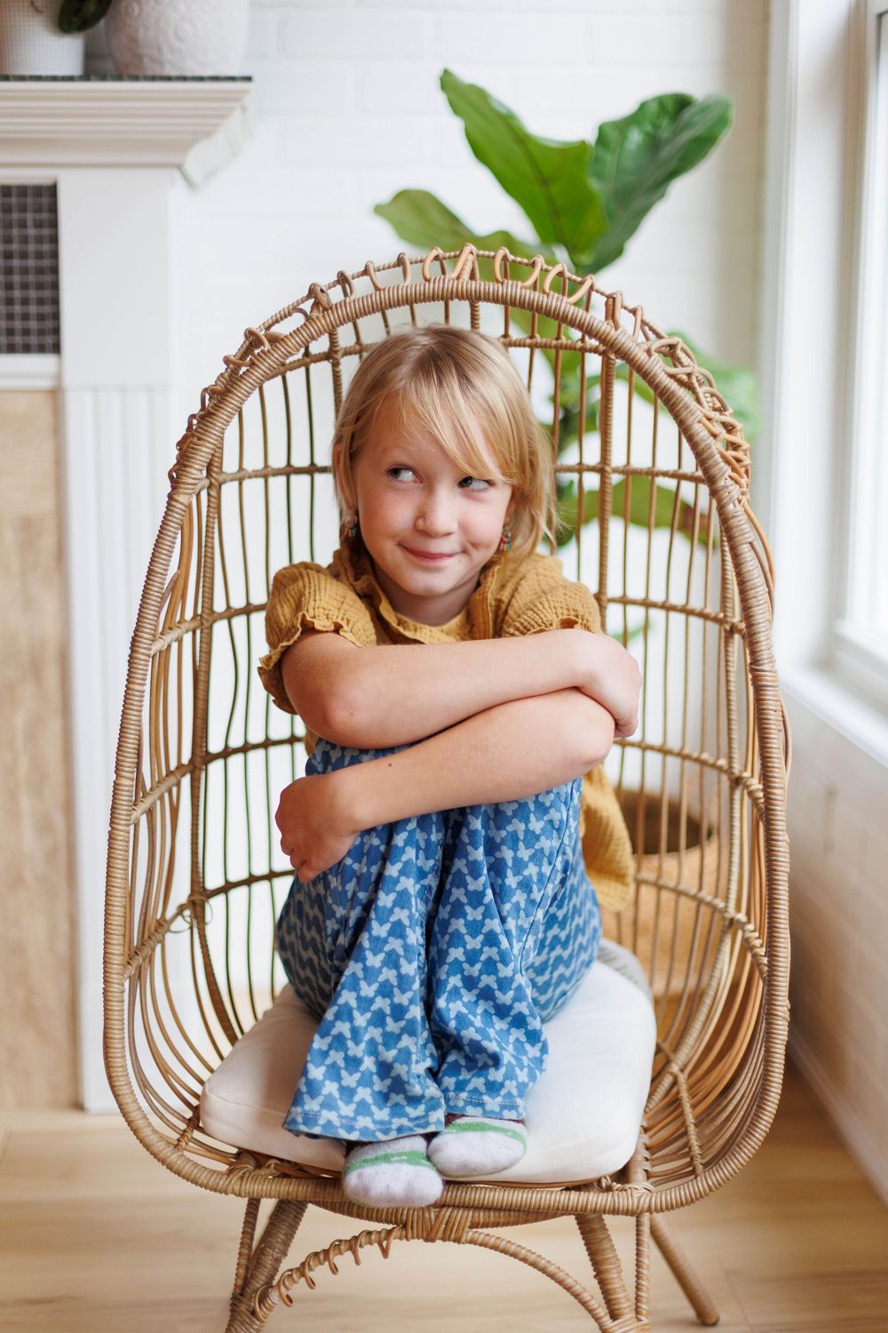 Four sequential photos show someone sitting curled up in a rattan chair with a blue and white patterned dress.