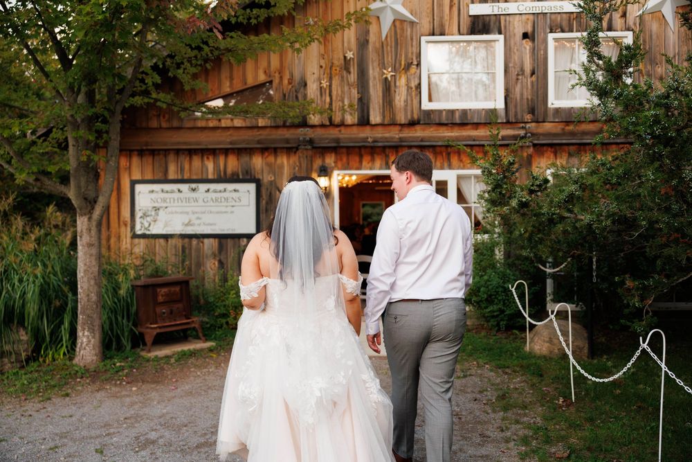 A couple walking together towards a rustic wooden barn entrance on their wedding day.