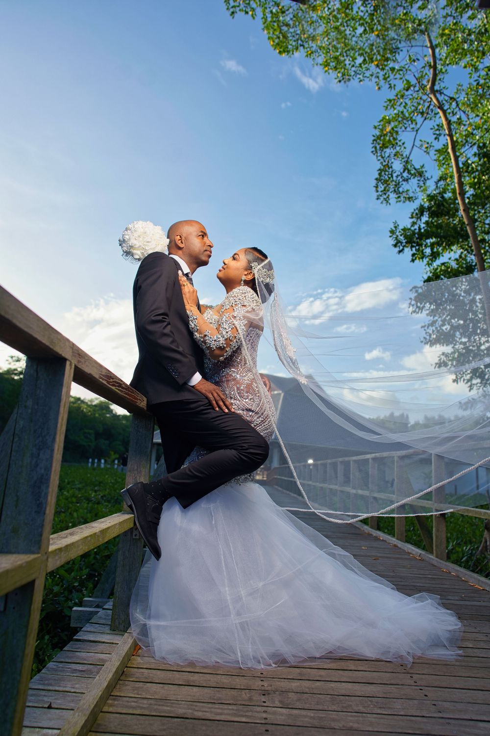 A romantic wedding photo sequence showing a couple dipping and embracing on a wooden boardwalk with flowing veil.