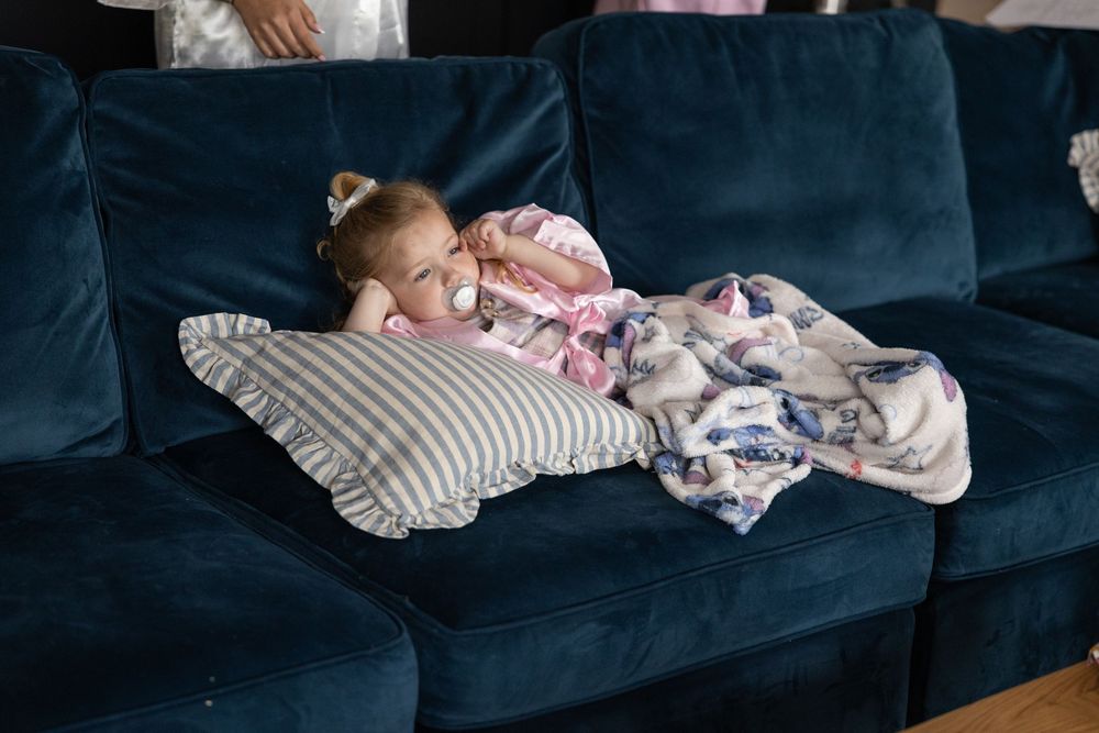 Sleeping baby wrapped in blankets rests peacefully on blue couch.