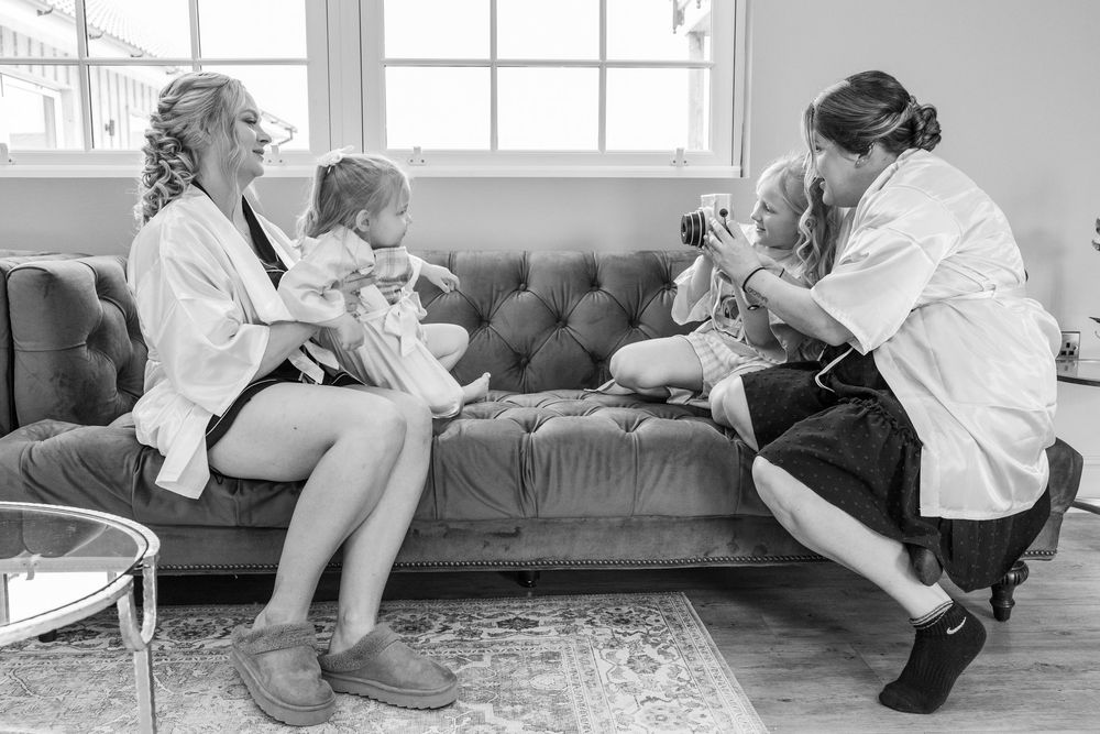 Wedding preparation scene with white robes and casual moments captured in black and white.