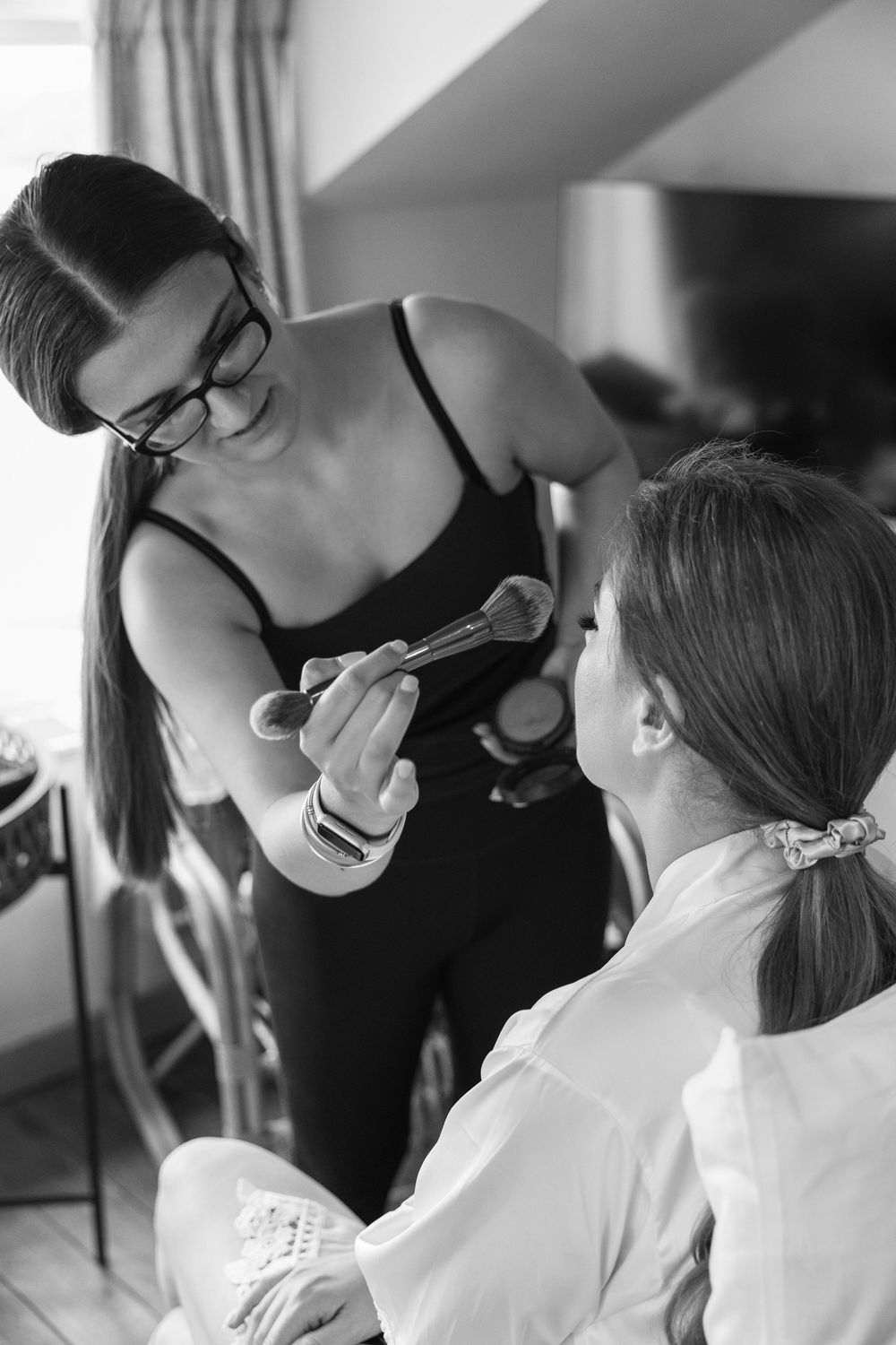 Professional makeup artist applying cosmetics to a client in preparation for a special event.