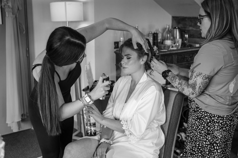 Wedding party getting ready in a bright room with matching white robes.
