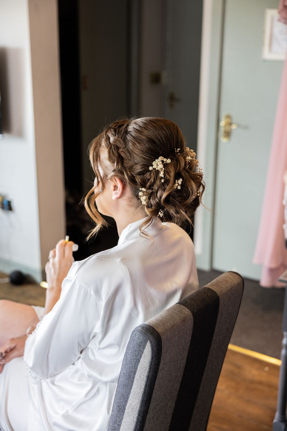 Wedding preparations showing someone getting hair styled with delicate gold floral accessories.