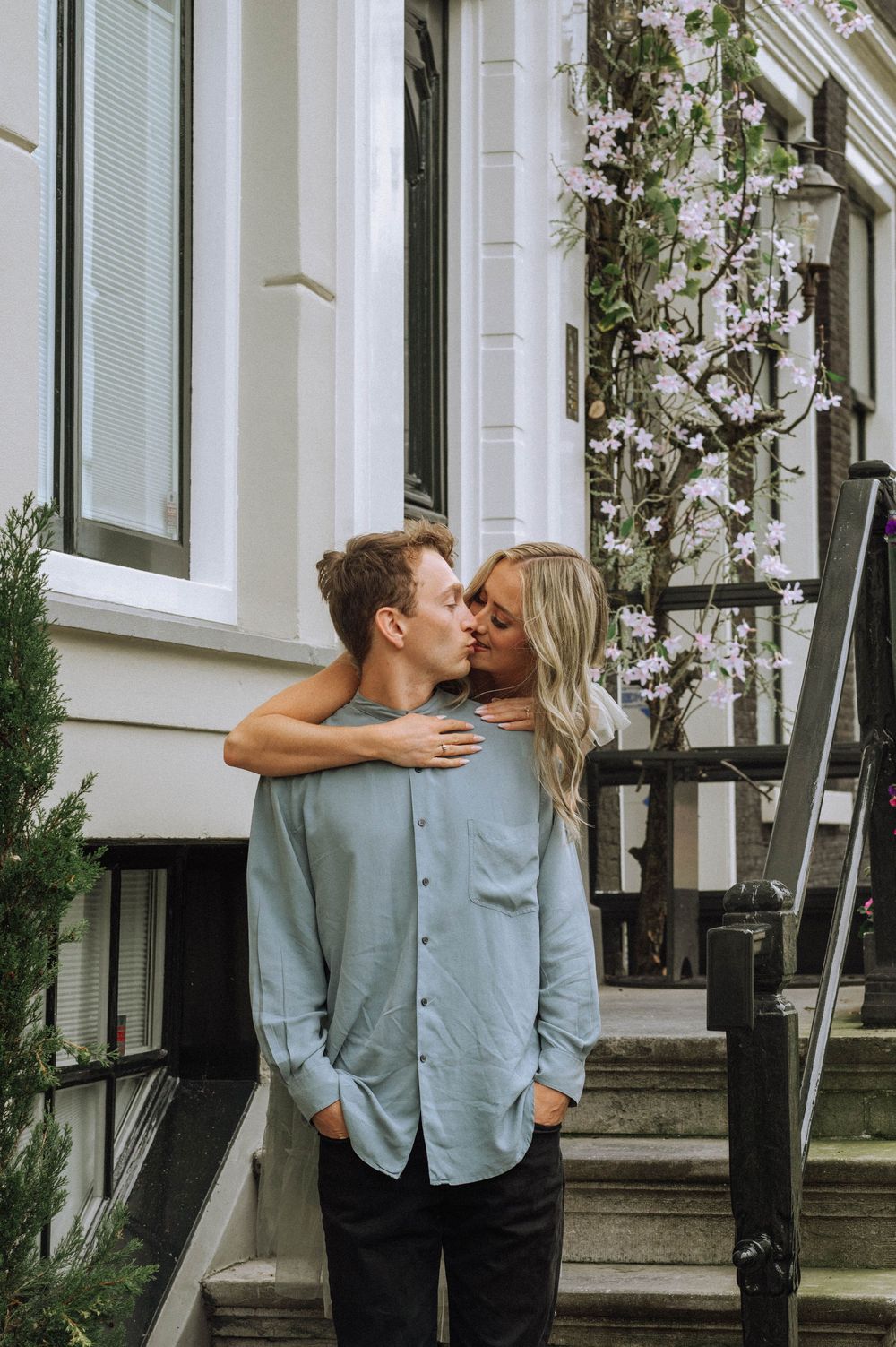 A romantic couple embraces and kisses in front of a white building with steps in a series of connected photos.