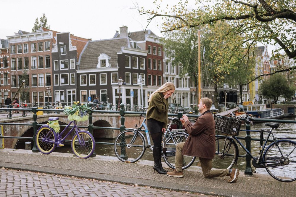 Historic Dutch canal with traditional architecture, bicycles parked along bridge railings and autumn trees in Amsterdam.