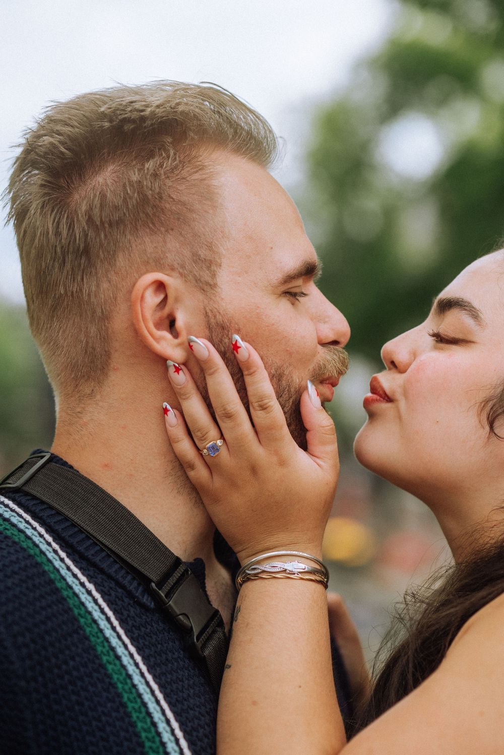 A romantic couple sharing an intimate kiss outdoors in a natural setting.