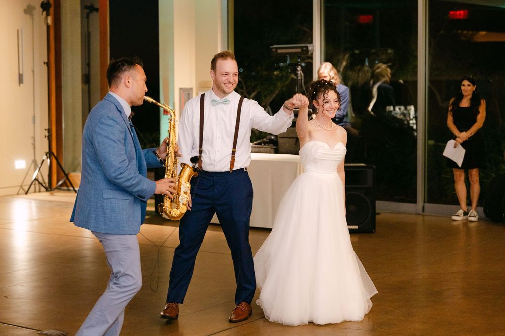 Wedding guests dance and celebrate on a spacious dance floor at an elegant indoor reception venue.