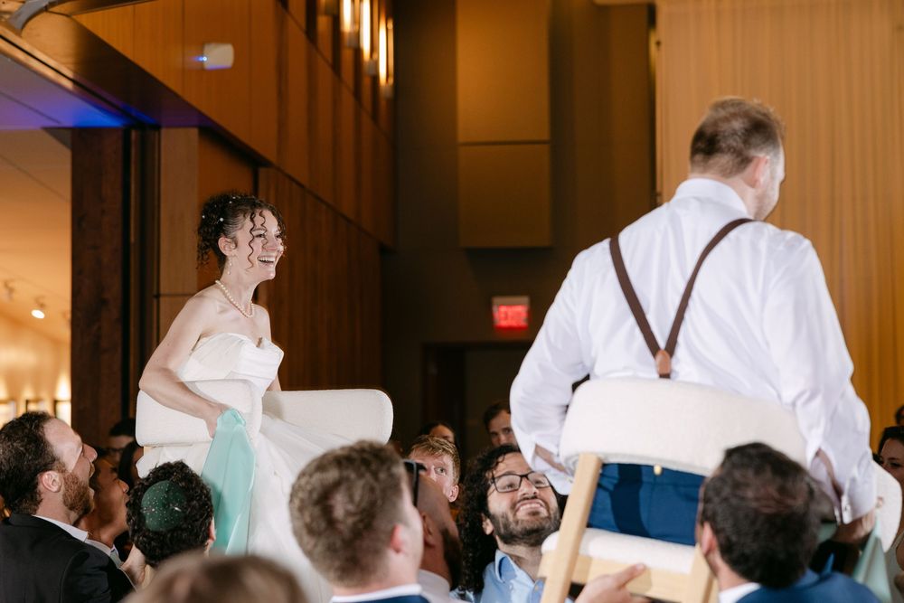 Wedding party members perform choreographed dance moves during a lively reception celebration.