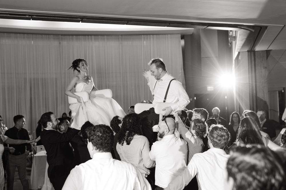 Wedding guests dancing and celebrating on the dance floor at an indoor reception venue.