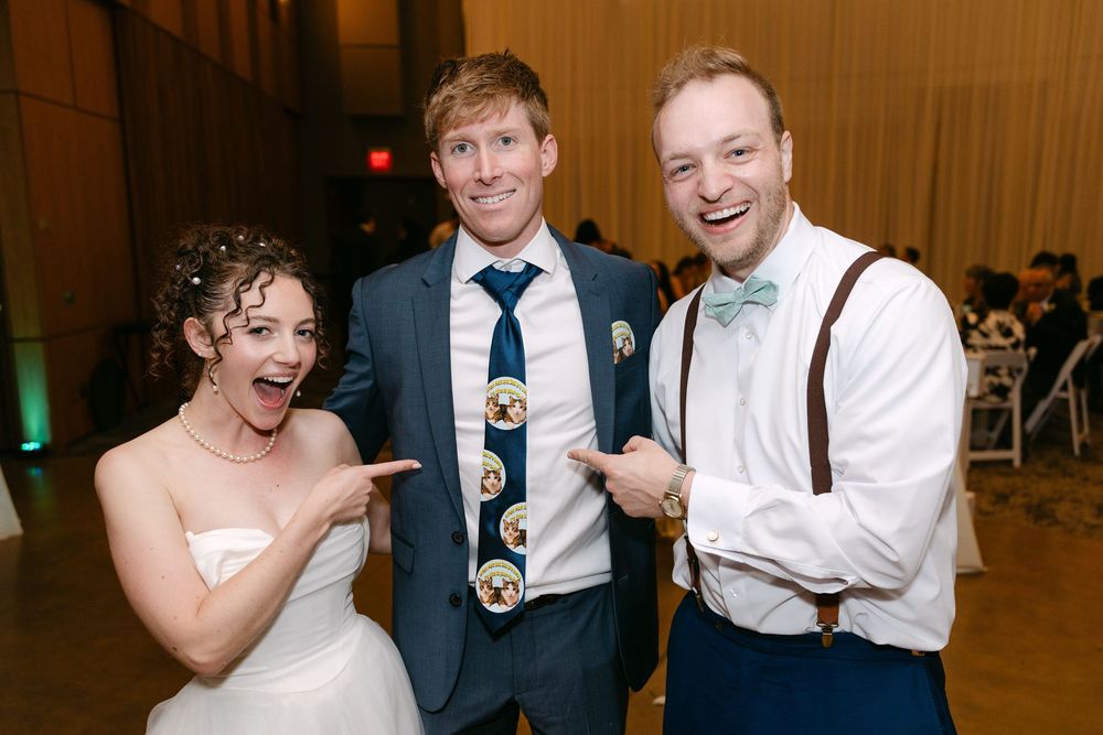 Wedding party dancing and celebrating together on a wooden dance floor at an indoor reception venue.