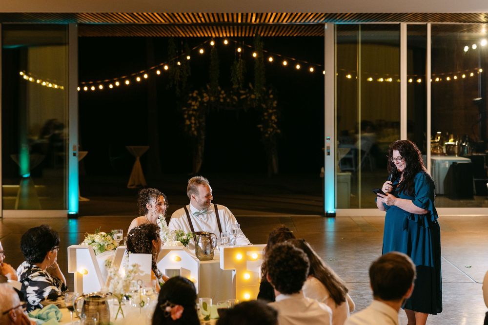 String lights illuminate a dark reception venue as guests dance and celebrate.