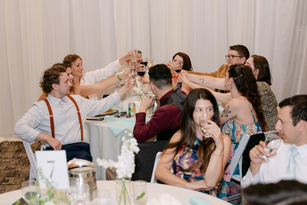 Wedding guests seated at tables enjoying dinner and conversation at reception.