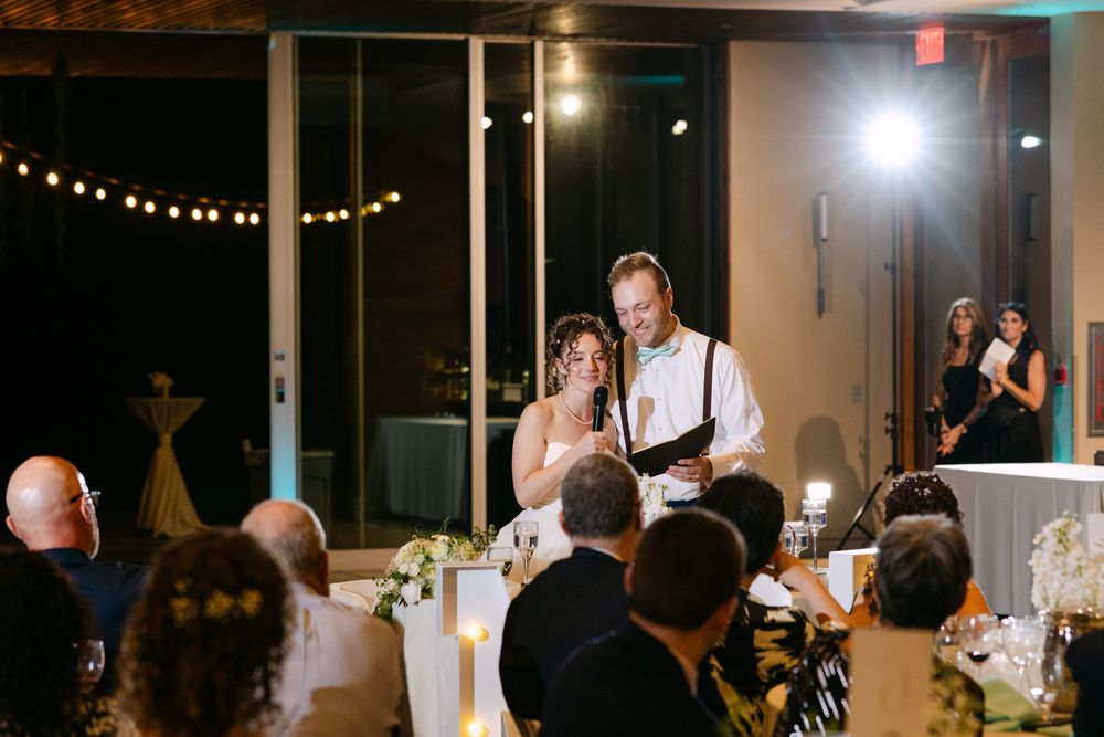 Evening wedding reception venue with string lights and large windows creating a romantic atmosphere.