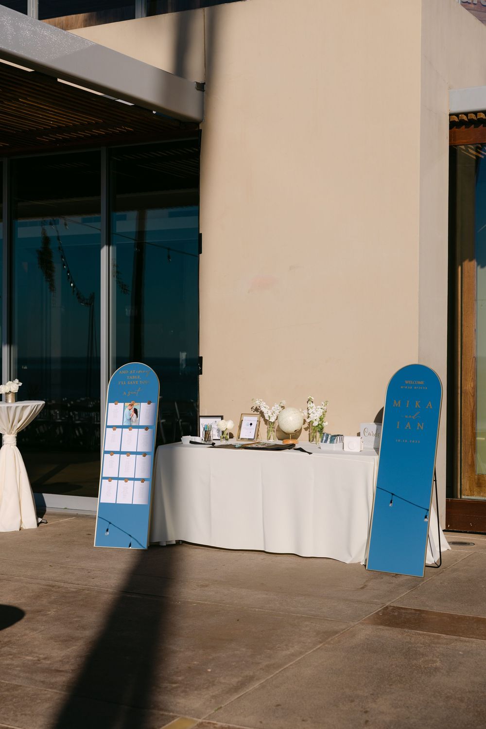 Empty wedding venue setup with blue doors and white tables against a wall.
