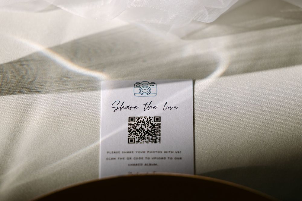 A QR code on a white card with 'Share the love' text sits on a fabric surface with light flares.