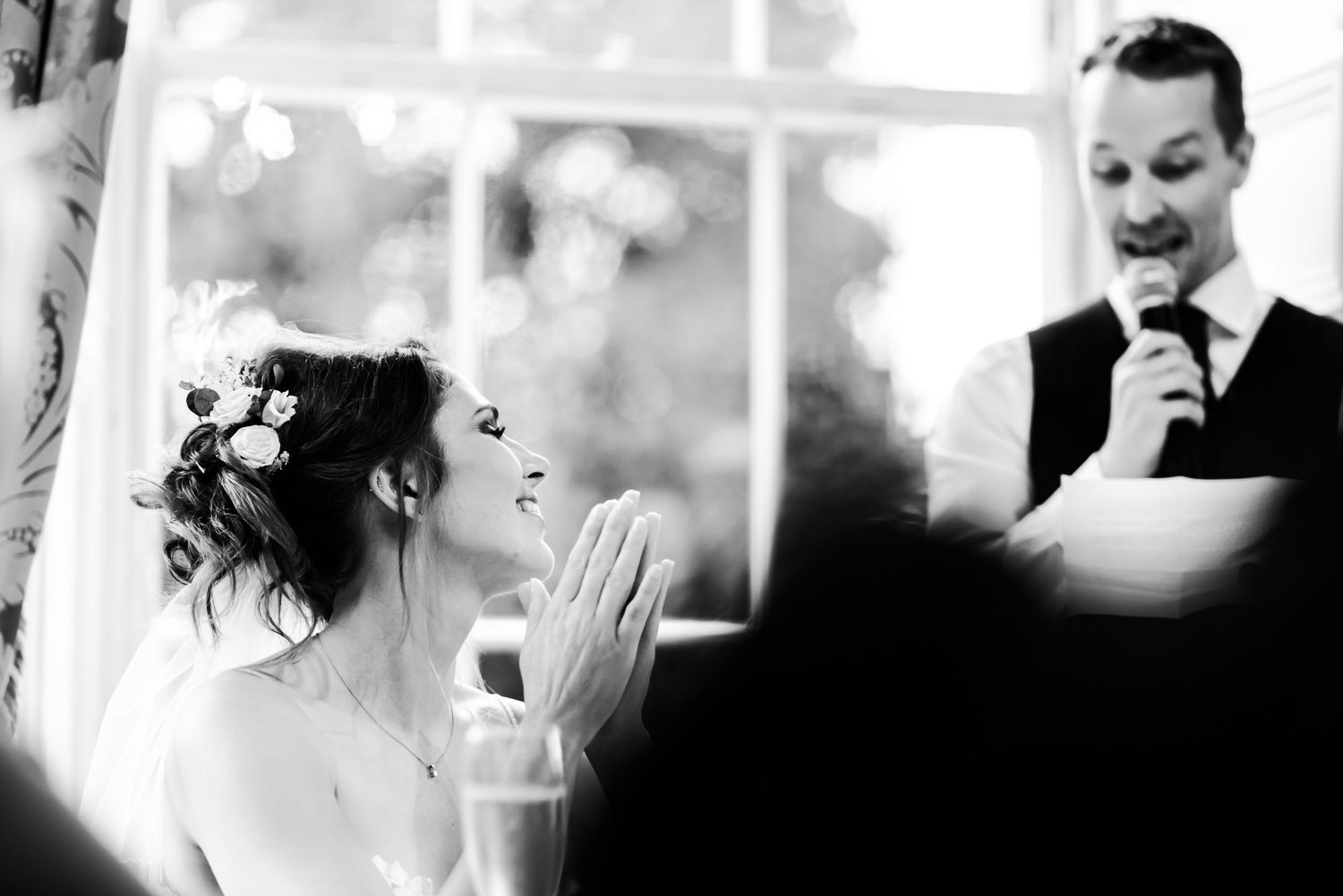 A candid black and white wedding photograph capturing laughter and joy during a celebration.