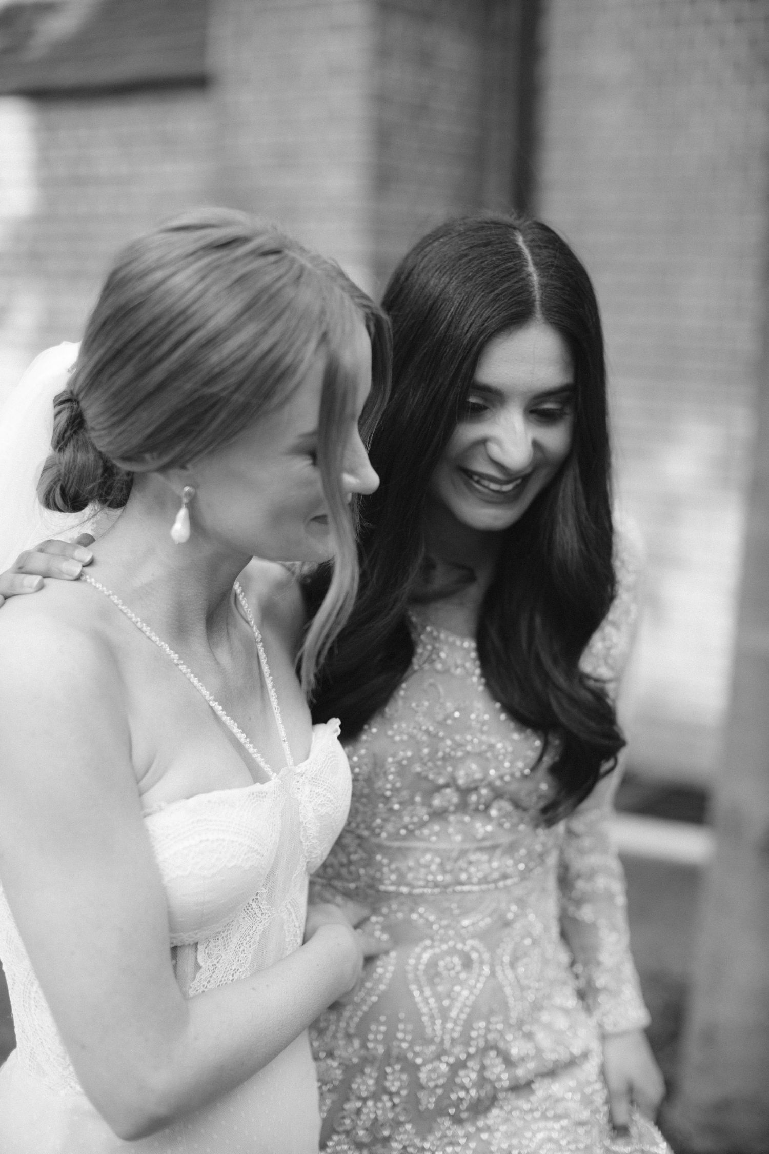 Two brides share a moment together at a Halifax wedding near The Lord Nelson Hotel, one in a white dress and one in a sparkly beaded gown.