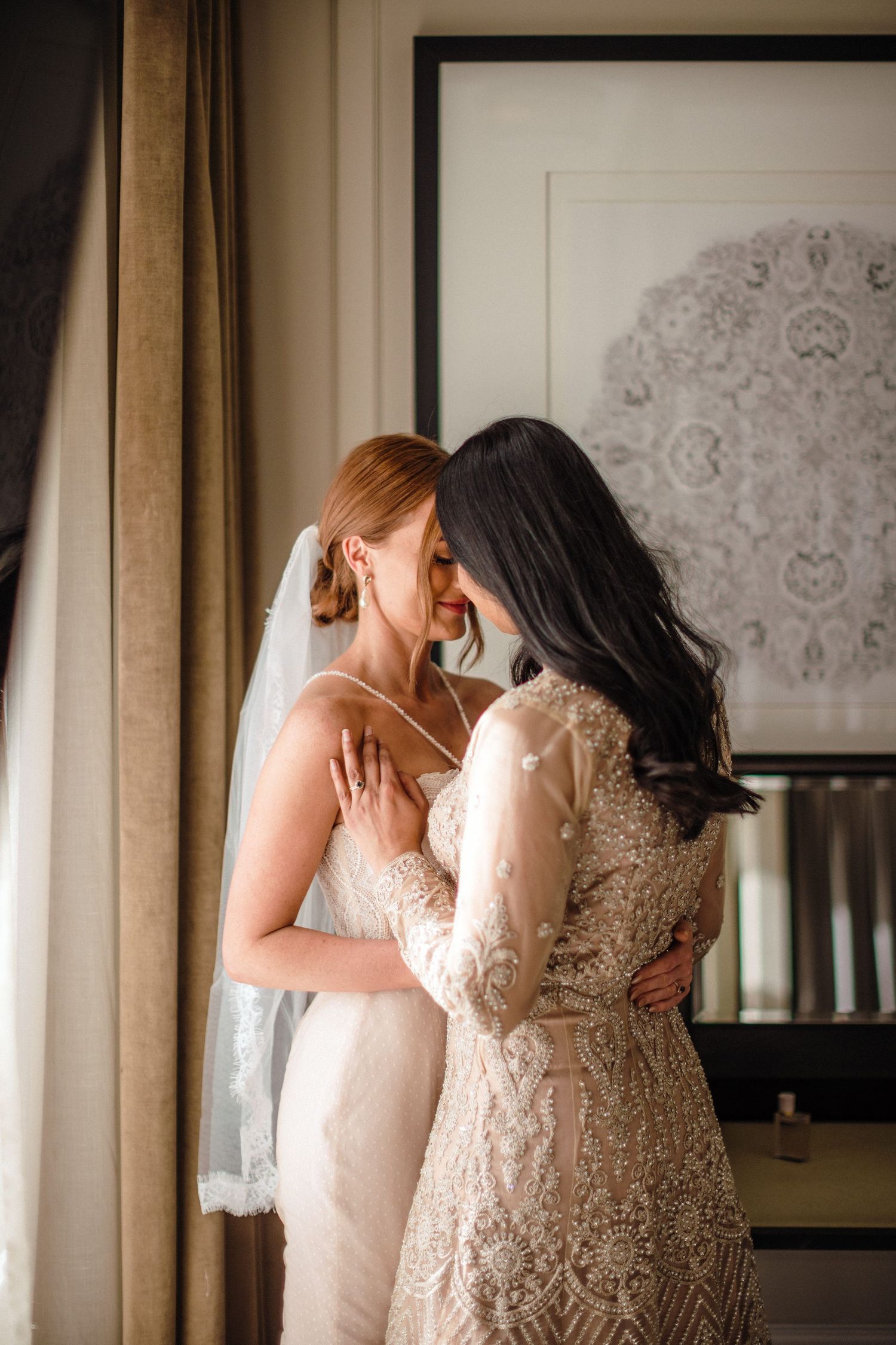 An intimate LGBTQ wedding moment captured near a window with elegant lace dresses and soft natural light at The Lord Nelson, Halifax