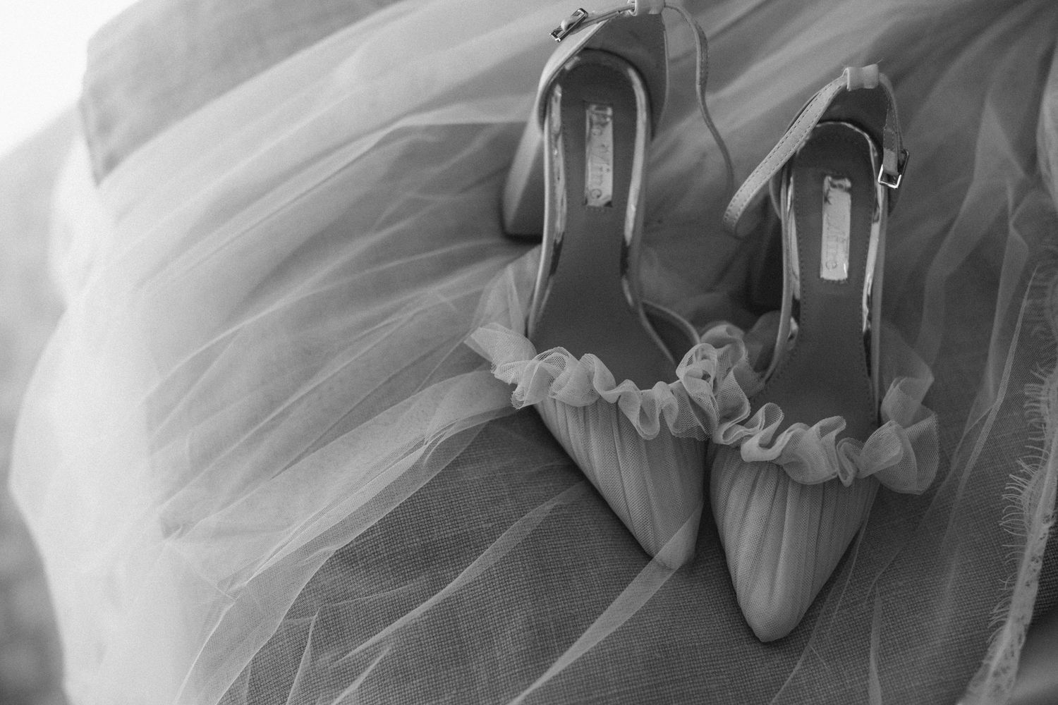 Elegant silver bridal shoes resting on layers of white tulle fabric in black and white photography at The Lord Nelson, Halifax