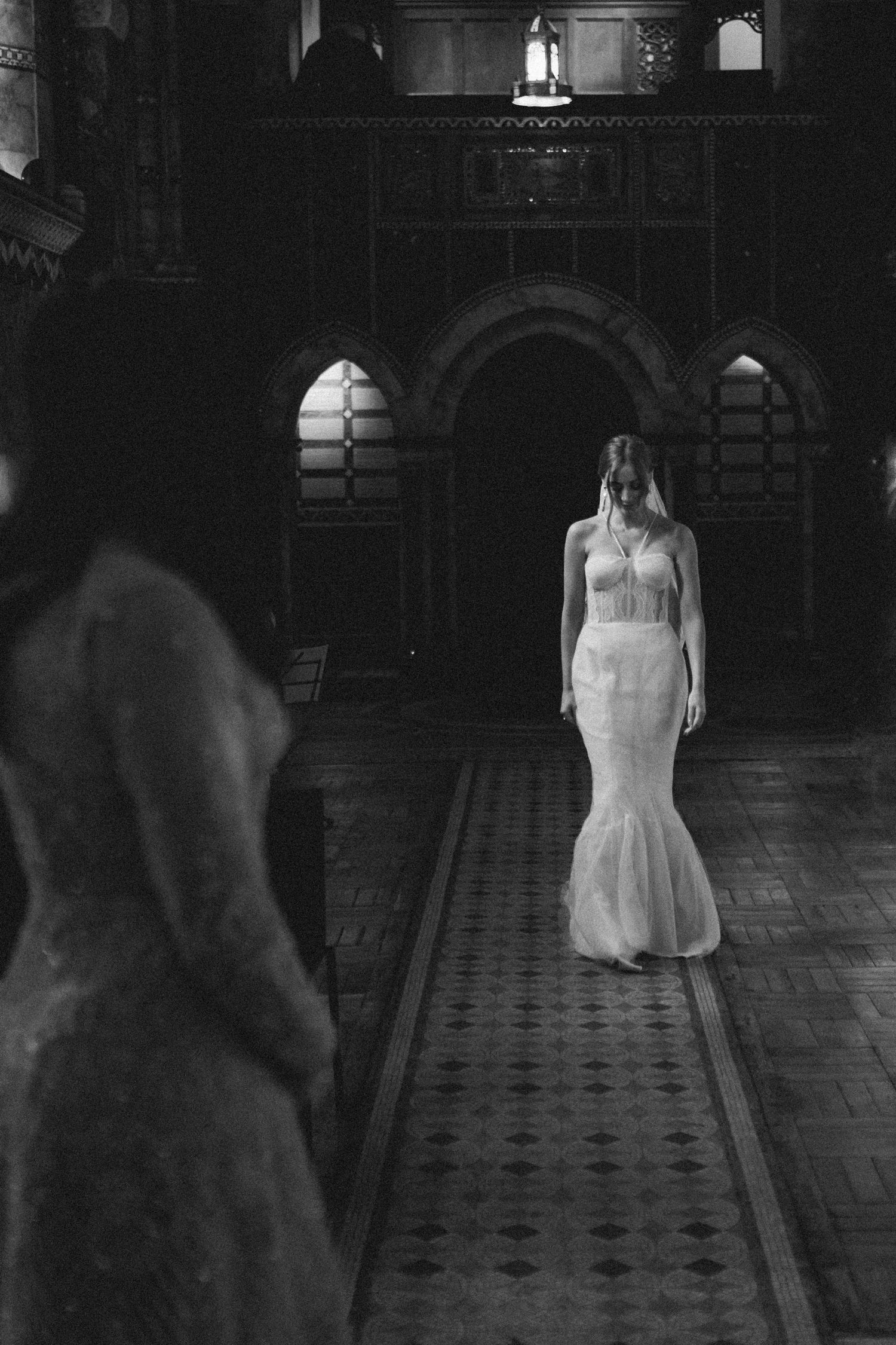 Black and white photo of bride in mermaid wedding gown walking down ornate church aisle in Halifax Nova Scotia.