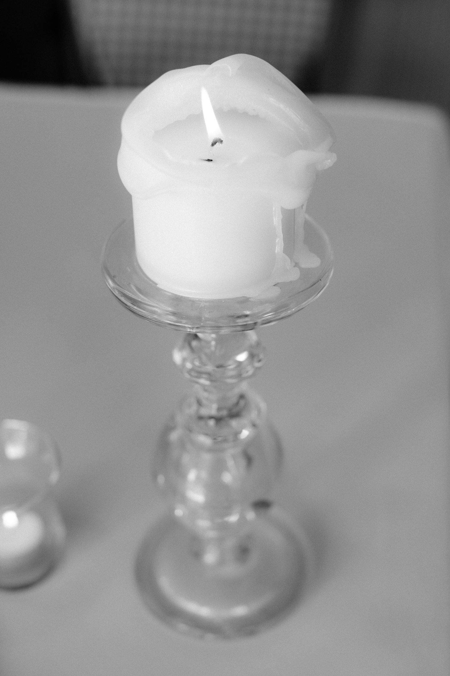 A white pillar candle burning on a crystal candlestick holder in monochrome at The Lord Nelson, Halifax