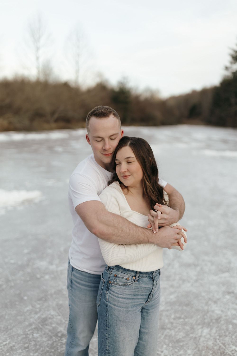 A romantic couple embraces on a frozen lake during a winter photo session.