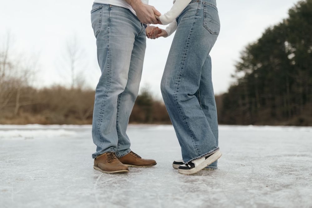 Close-up of two pairs of feet standing together on icy ground.
