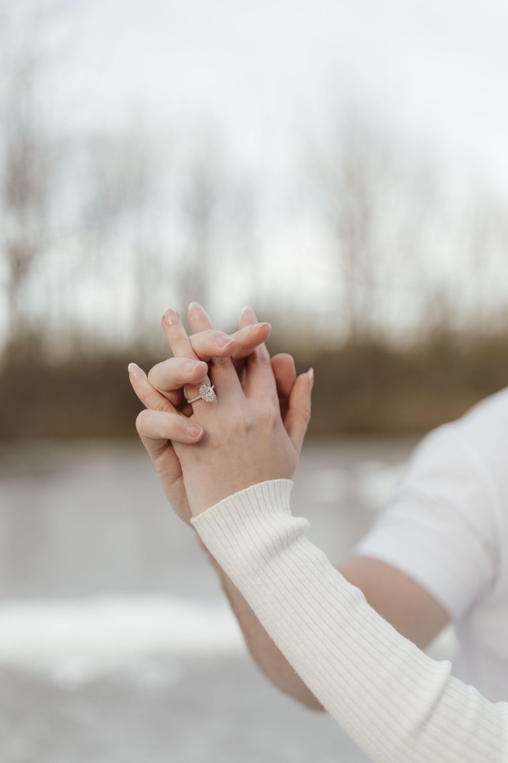 Close-up of intertwined hands against winter landscape background.