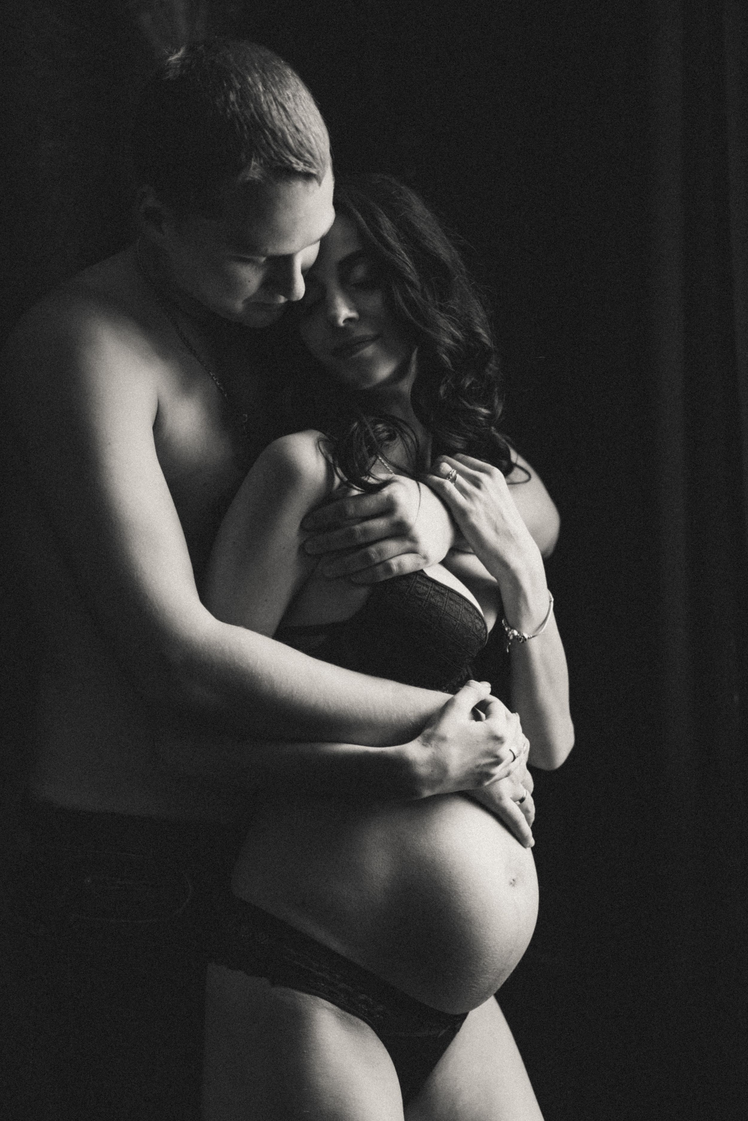 Dramatic black and white maternity photos capturing intimate moments in moody lighting.