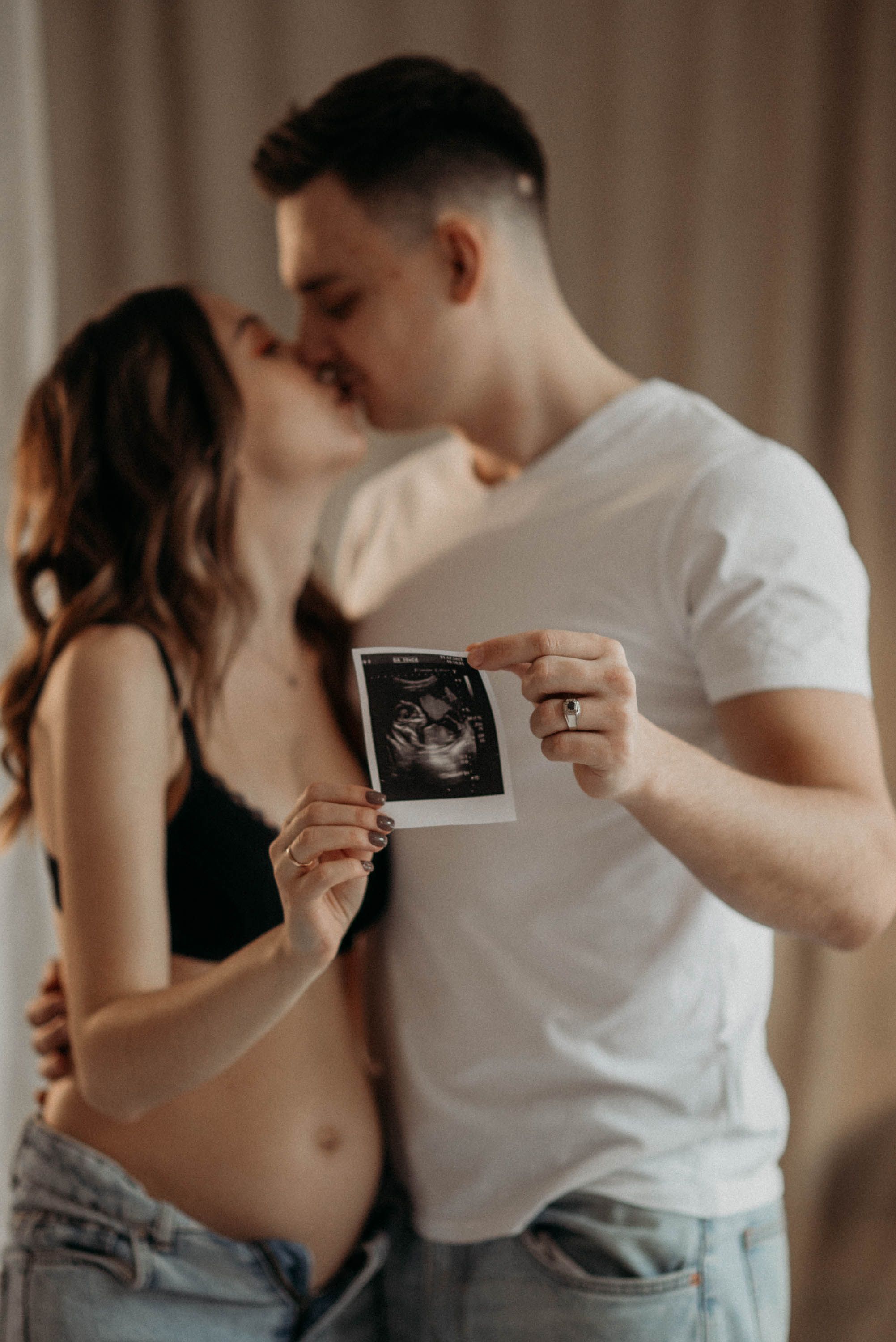 Couple in casual attire sharing an intimate moment while looking at a photo.