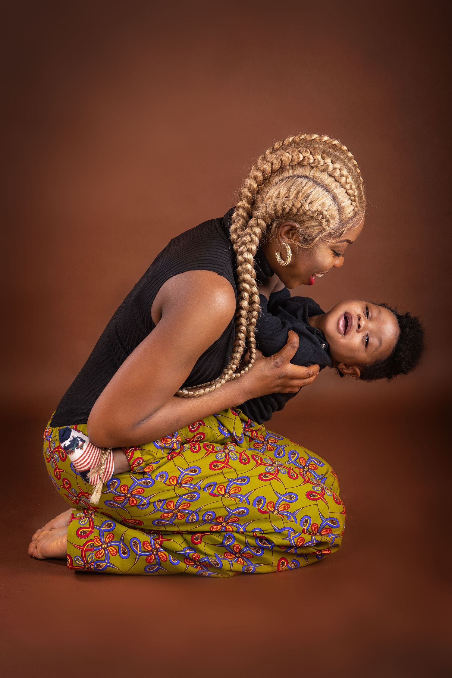 A mum with her toddler son laughing with the brown background