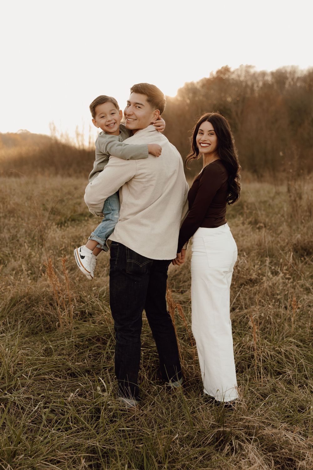 Casual family photo session with parents and children, captured in a lush park setting.